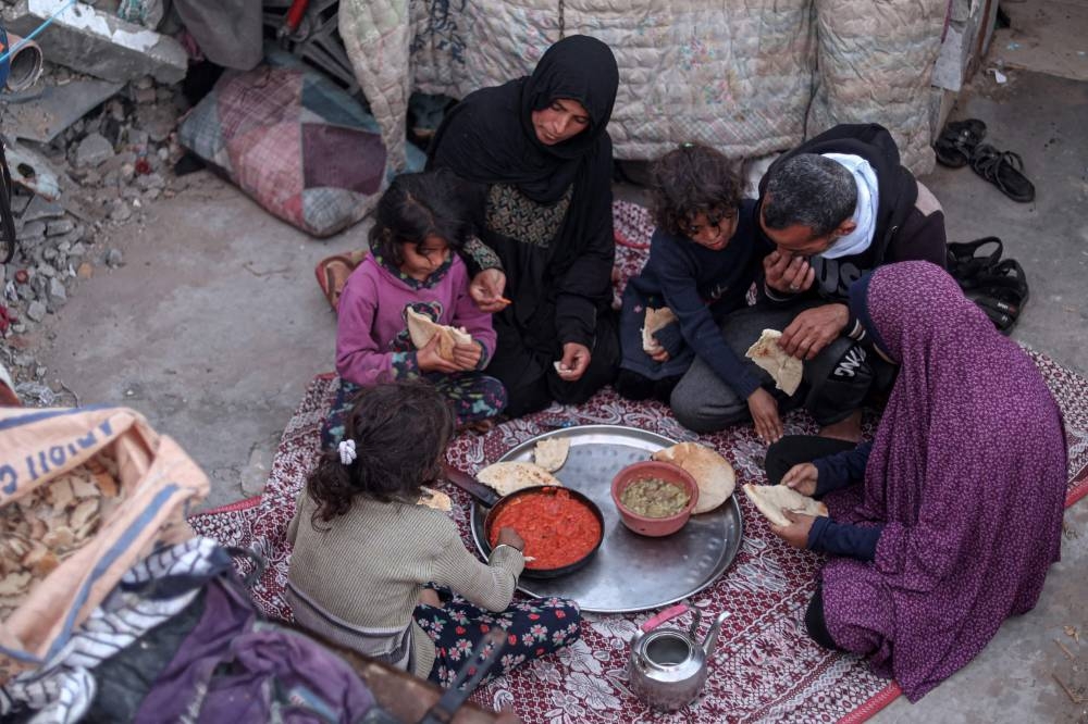 Members of the Rabaya family break their fast amidst the rubble of their home, which was destroyed by an Israeli strike,  on Saturday. AFP
