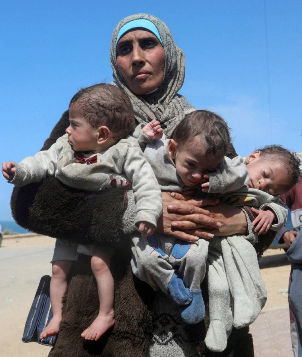 Palestinian woman Nozha Awad flees Al Shifa hospital following an Israeli raid with her triplet children, moving southward in the central Gaza Strip, on Thursday. REUTERS