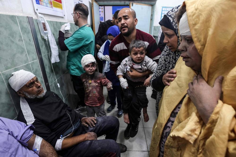 A man carries children injured in Israeli bombardment, at the al-Najjar hospital in Rafah in the southern Gaza Strip on Sunday. AFP