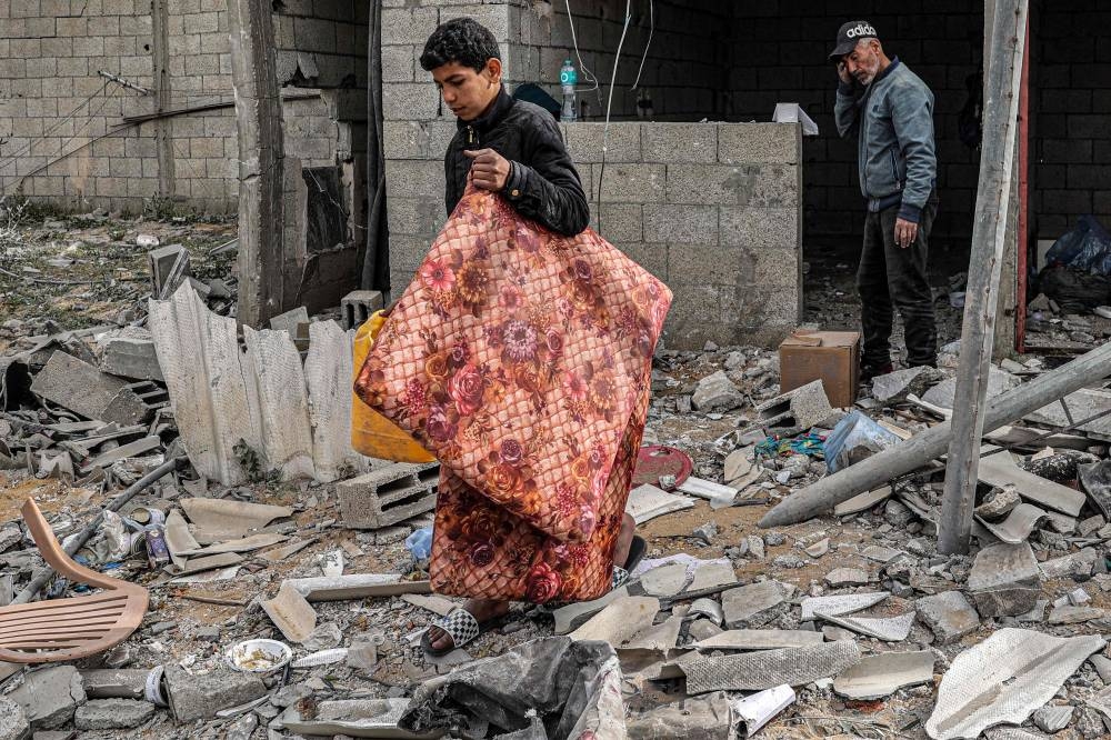 A boy salvages a mattress from the rubble of a building that was hit overnight during Israeli bombardment in Rafah in the southern Gaza Strip on Tuesday. AFP