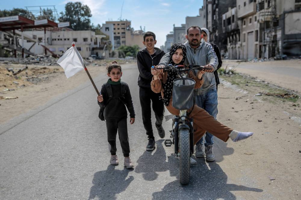 A girl holds a white flag as a displaced Palestinian family walks in Gaza City, on Monday. AFP