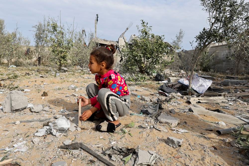 A Palestinian child sits at the site of an Israeli strike on a house in Rafah, in the southern Gaza Strip, on Tuesday. REUTERS