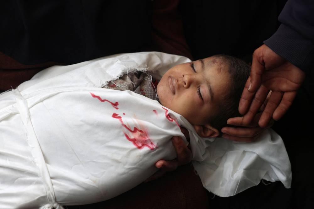 Palestinians mourn over the body of a child, killed in Israeli bombardment the night before, the European hospital in Khan Yunis in the southern Gaza Strip, on Friday. AFP