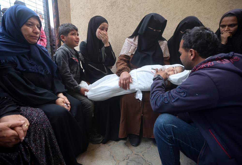Mourners react next to the body of a Palestinian child killed in an Israeli strike in Khan Younis in the southern Gaza Strip on Friday. REUTERS