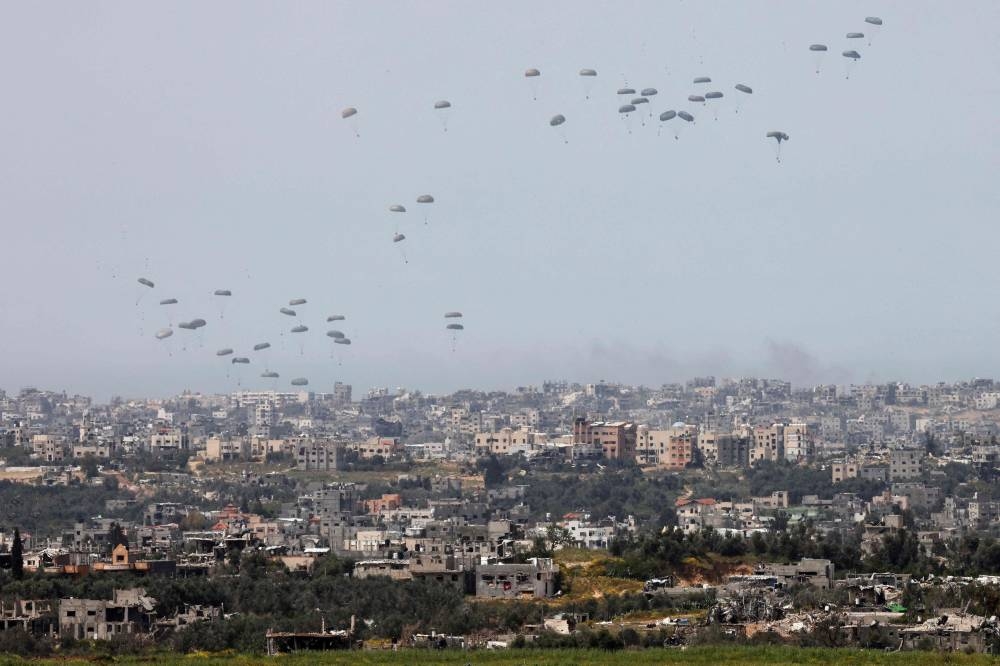This picture taken from Israel's southern border with the Gaza Strip shows a military aircraft releasing parachutes of humanitarian aid over the besieged Palestinian territory on Wednesday. AFP