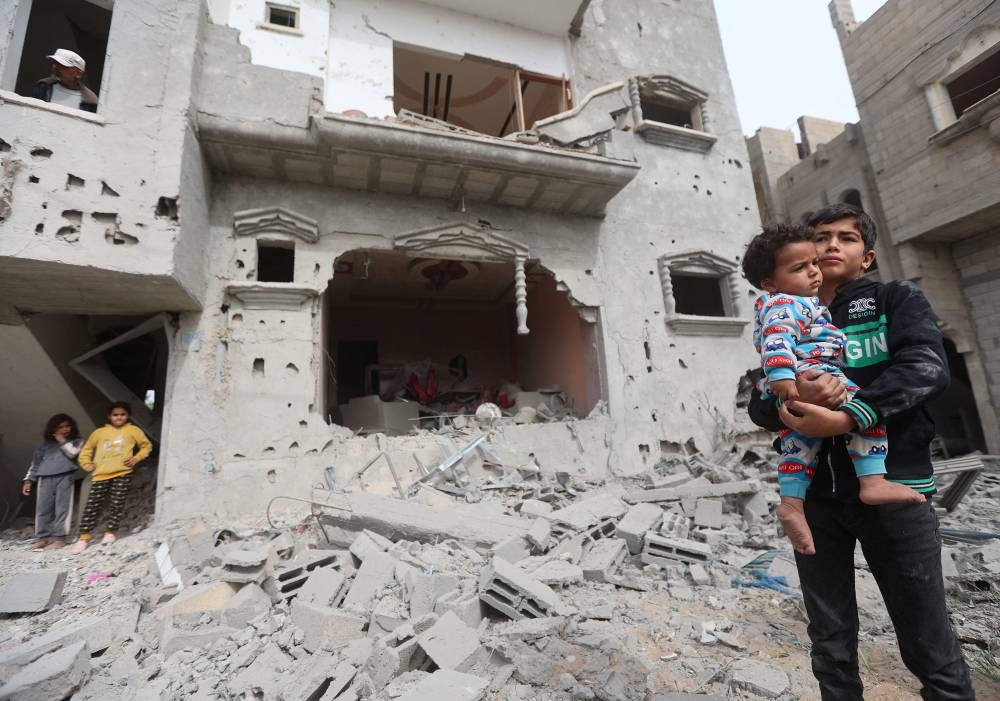 Palestinian children react at the site of an Israeli strike on a house in Khan Younis in the southern Gaza Strip Saturday. REUTERS