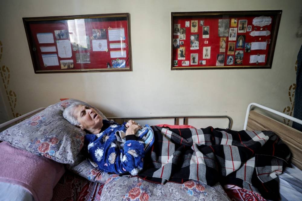 Palestinian Christian Violette Masoud, who was displaced from her house due to Israel's military offensive, lies on a bed at the Holy Family church where she takes shelter, as Gaza Christians mark Easter amid muted festivities due to the ongoing conflict between Israel and Hamas, in Gaza City, on Thursday. REUTERS