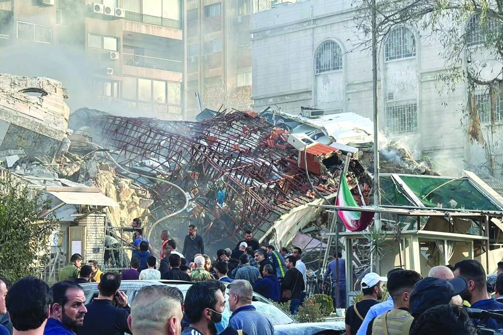 Security personnel gather at the site of strikes which hit a building next to the Iranian embassy in Syria's capital Damascus, Smoke rises after the Israeli strike on a building close to the Iranian embassy in Damascus, Monday.