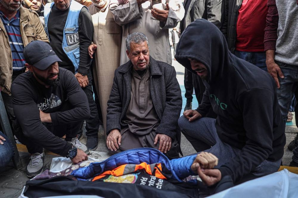 Relatives and friends mourn by the body of Saif Abu Taha, a staff member of the US-based aid group World Central Kitchen who was killed as Israeli strikes hit a convoy of the NGO delivering food aid in Gaza a day earlier, during his funeral in Rafah in the southern Gaza Strip on Tuesday. AFP