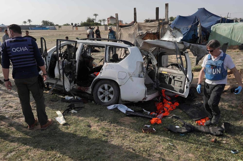 United Nations staff members inspect the carcass of a car used by US-based aid group World Central Kitchen, that was hit by an Israeli strike the previous day in Deir al-Balah in the central Gaza Strip on Tuesday. AFP