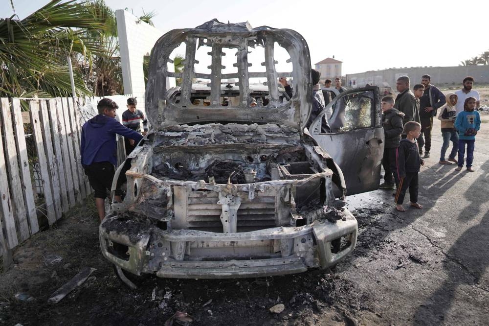 People gather around the car of the US-based aid group World Central Kitchen that was hit by an Israeli strike the previous day in Deir al-Balah in the central Gaza Strip on Tuesday. AFP
