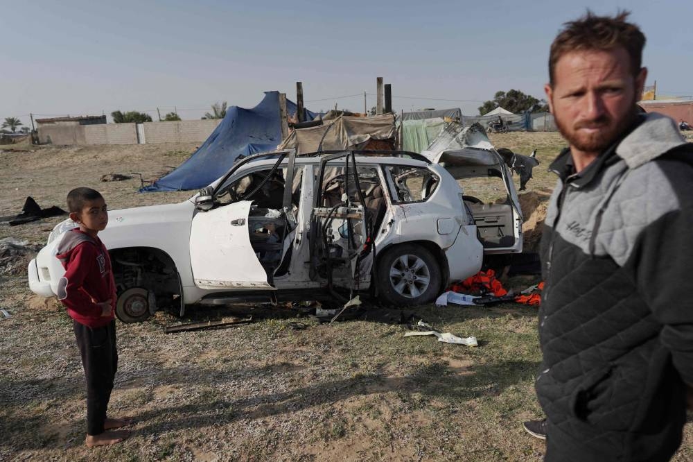 People gather around the carcass of a car used by US-based aid group World Central Kitchen, that was hit by an Israeli strike the previous day in Deir al-Balah in the central Gaza Strip on Tuesday. AFP
