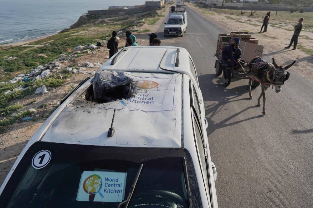 People gather around the carcass of a car used by US-based aid group World Central Kitchen, that was hit by an Israeli strike the previous day in Deir al-Balah in the central Gaza Strip on Tuesday. REUTERS