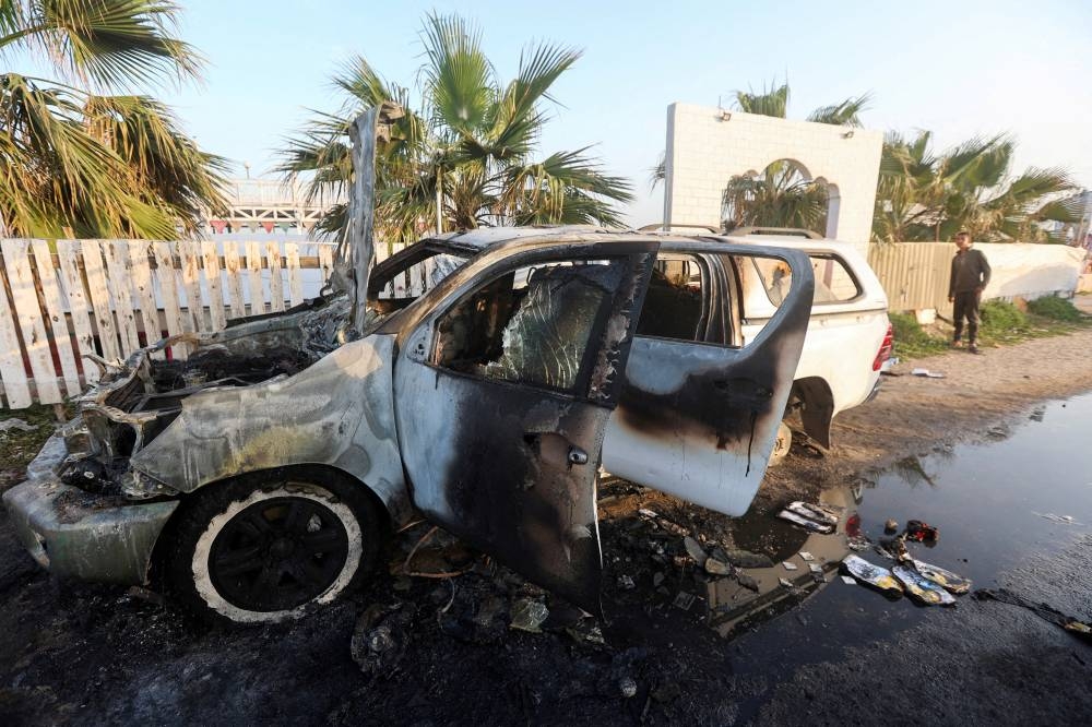 A person looks at a vehicle where employees from the World Central Kitchen (WCK), including foreigners, were killed in an Israeli airstrike in Deir Al-Balah, in the central Gaza, Strip ON April 2. REUTERS