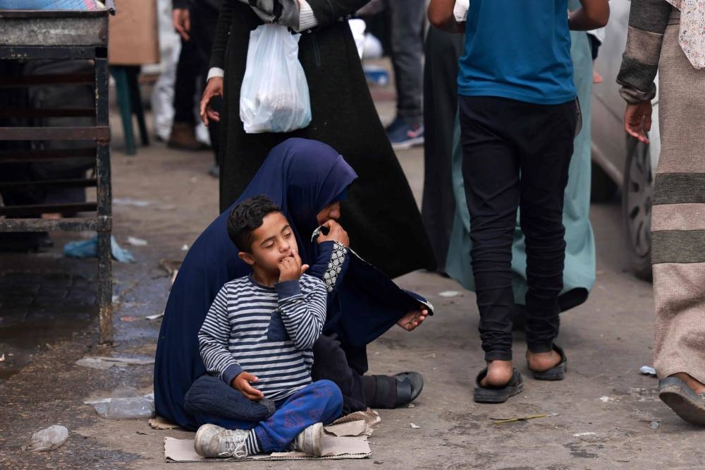 A Palestinian child sits next to a woman begging in a market, ahead of Eid al-Fitr celebrations, in Rafah in the southern Gaza Strip on Saturday. AFP