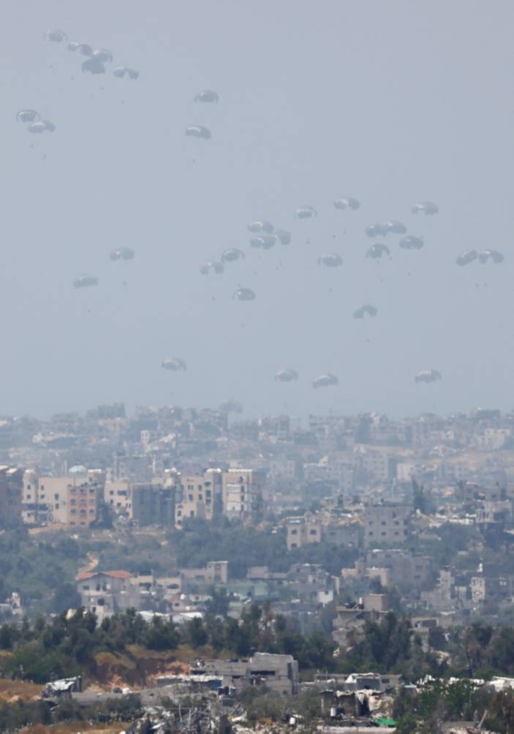 Humanitarian aid falls through the sky towards the Gaza Strip after being dropped from an aircraft, as seen from Israel, on Sunday. REUTERS