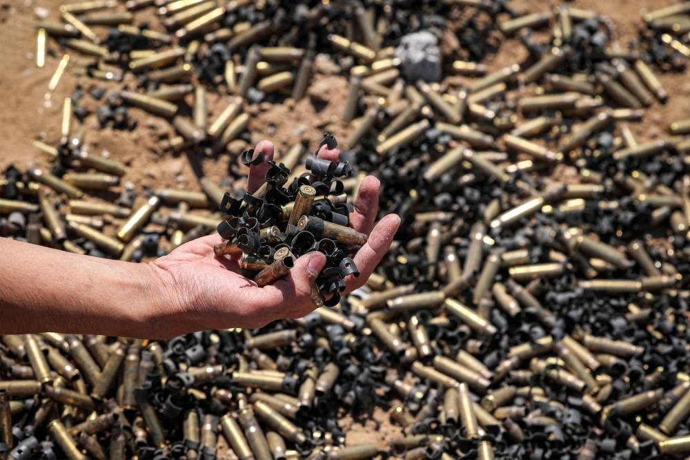 A person holds a handful of spent bullet casings above a bigger pile in Khan Yunis on Sunday after Israel pulled its ground forces out of the southern Gaza Strip, six months into the devastating war. AFP