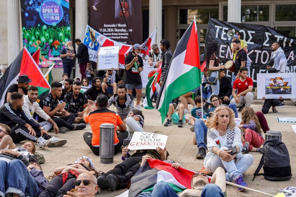 Protesters lie on the ground to mark a moment of silence outside the Nicosia Municipal Theatre during a demonstration in Nicosia Sunday.