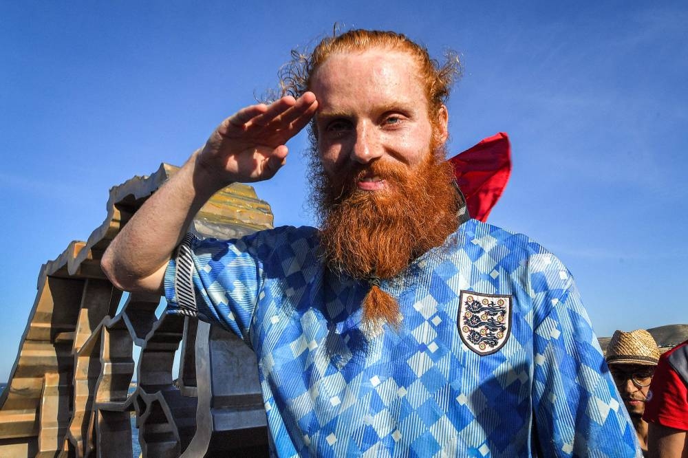 British runner Russ Cook gestures as he poses for a picture with the memorial sign marking the northern-most point of Africa upon arrival at Cape Angela, northeast of Tunis, Sunday while surrounded by supporters who joined him for the final leg of the 16,000 kilometre challenge to run across the African continent from South Africa's Cape Agulhas to Tunisia's Cape Angela to raise money for charity. AFP