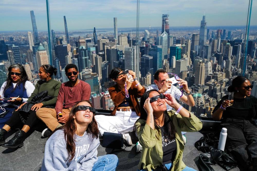 People look toward the sky at the 'Edge at Hudson Yards' observation deck ahead of a total solar eclipse across North America, in New York City on Monday. AFP