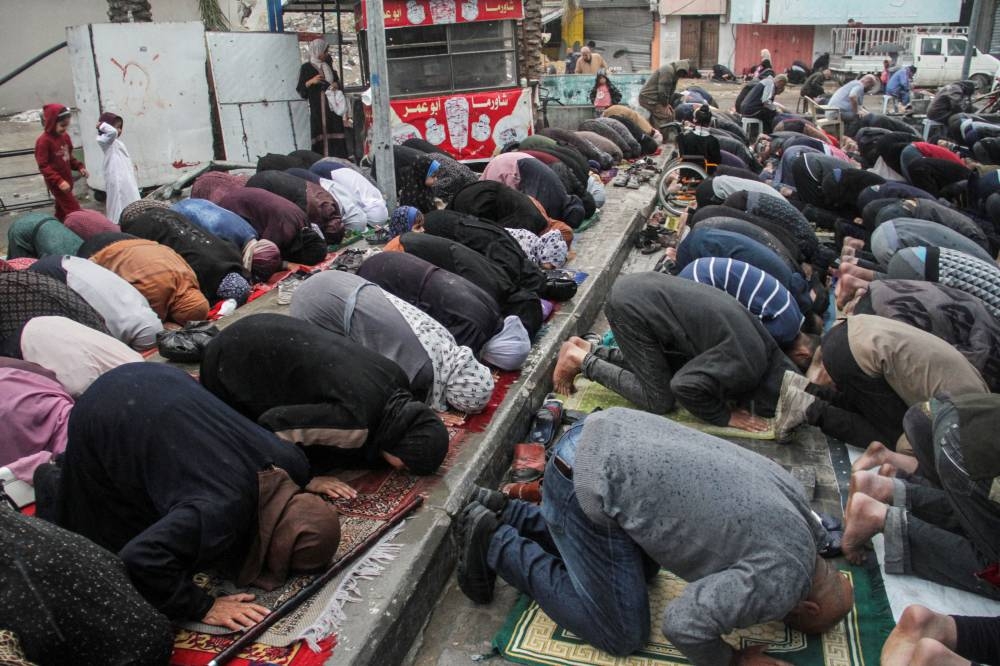 Palestinians attend Eid al-Fitr prayers during rain in northern Gaza, Wednesday.