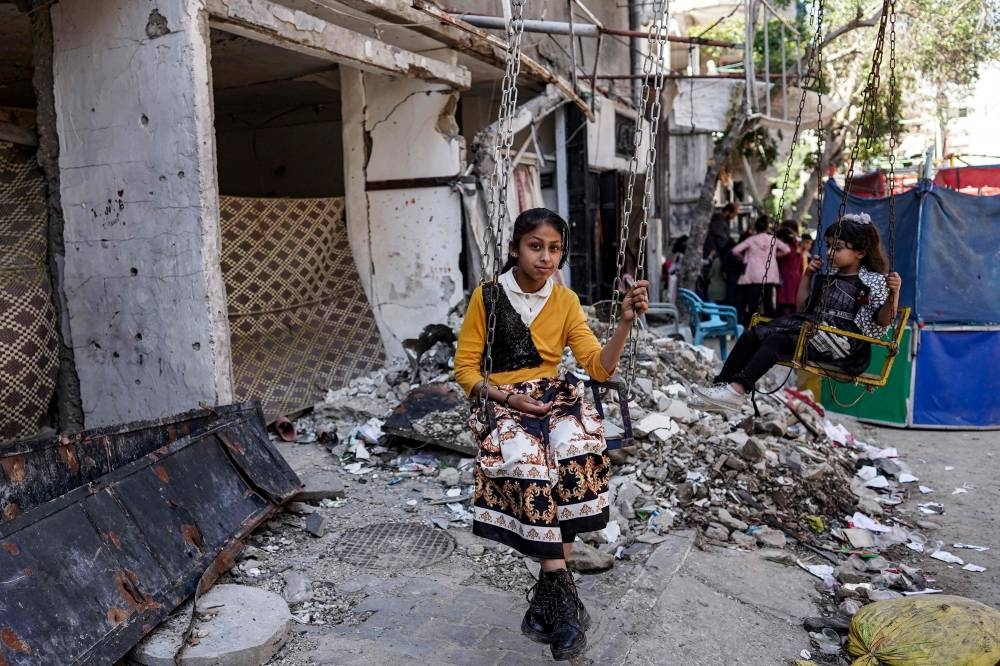A girl sits in a swing while celebrating on the first day of Eid al-Fitr, after the end of the holy month of Ramadan, in Deir el-Balah in the central Gaza Strip, Wednesday.