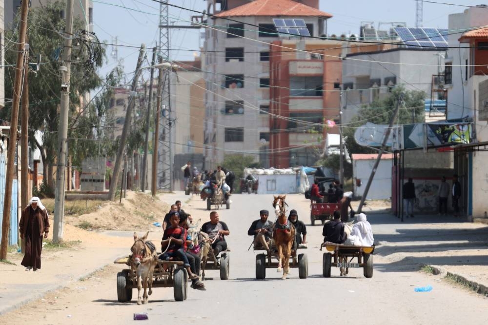 Palestinians transport belongings as people fleeing conflict leave their homes, in the Nuseirat refugee camp in central Gaza, on Friday. AFP