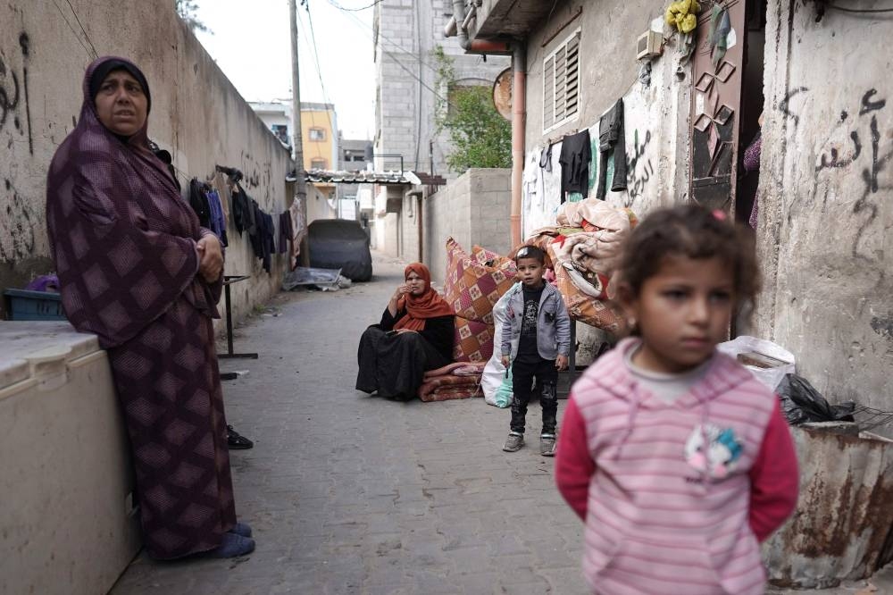 Palestinians stand near belongings as people fleeing conflict leave their homes, in the Nuseirat refugee camp in central Gaza, on Friday. AFP