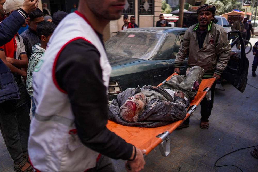 A man and a paramedic carry an injured man on a stretcher following Israeli bombardment in Nuseirat, central Gaza, on Friday. AFP
