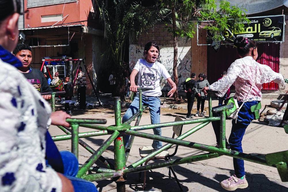 
Pictures show children sitting in a swing as they celebrate during the holiday of Eid al-Fitr, in Deir el-Balah in the central Gaza Strip. 
