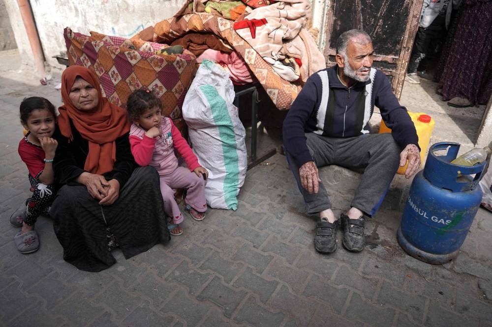 Palestinians sit near belongings as people fleeing conflict leave their homes, in the Nuseirat refugee camp in central Gaza on on Friday. AFP