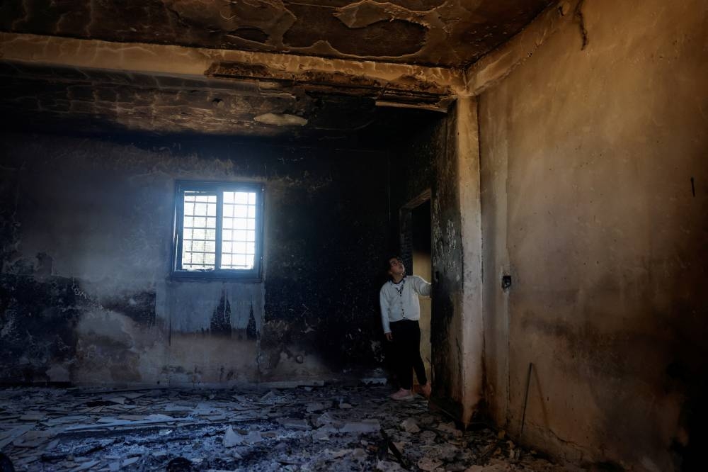 A Palestinian child inspects the damage to a house after Israeli settlers attacked the village of al-Mughayyer, in the Israeli-occupied West Bank, on Saturday. REUTERS