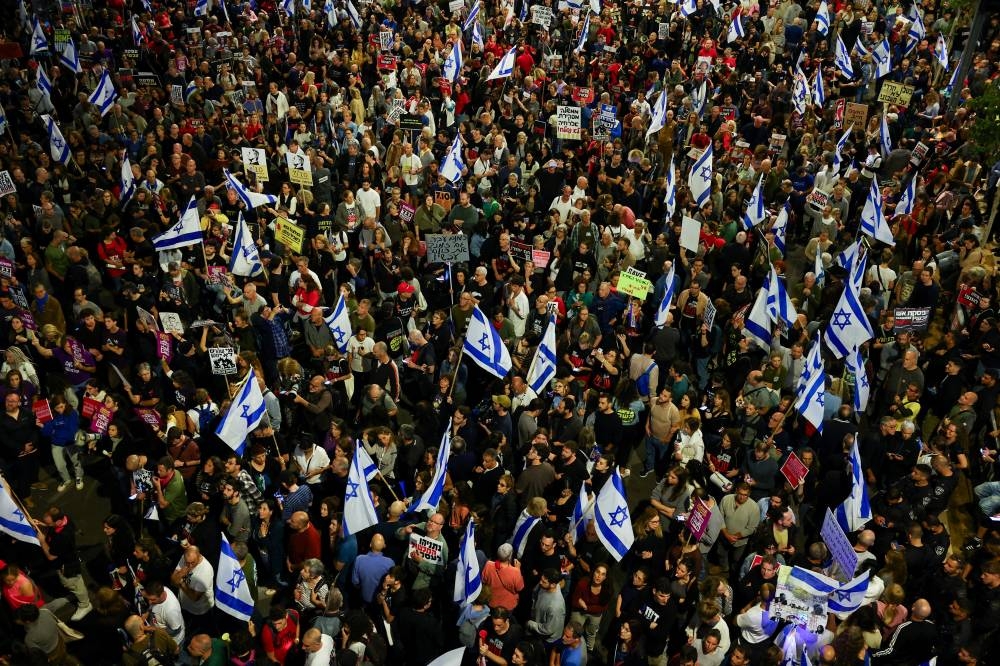 People hold Israeli flags as they attend a protest against Israeli Prime Minister Benjamin Netanyahu's government and to call for the release of hostages, in Tel Aviv, Israel, on Saturday. REUTERS