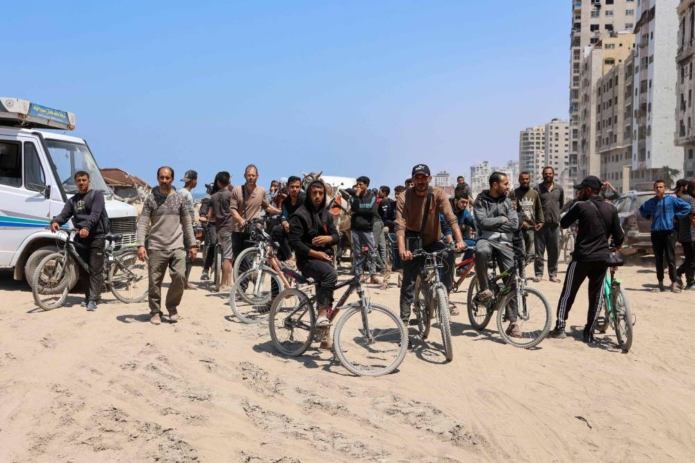 People wait on Sunday, for displaced Palestinians returning to Gaza City after fleeing northern Gaza following hostilities. AFP
