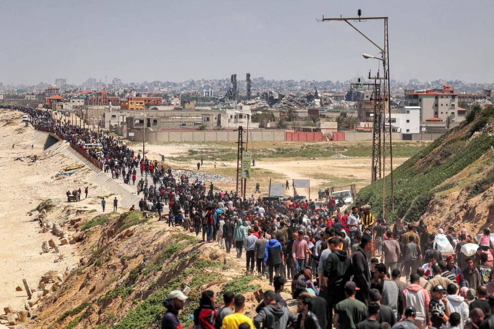Displaced Palestinians take the coastal Rashid road to return to Gaza City as they pass through Nuseirat in the central Gaza Strip on Sunday. AFP