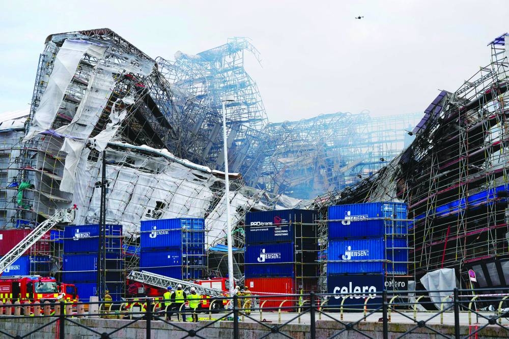 
Firefighters stand nearby as the outer wall of the historic former stock exchange Borsen in Copenhagen collapses, two days after a fire broke out that burned about half of the 17th century building. 