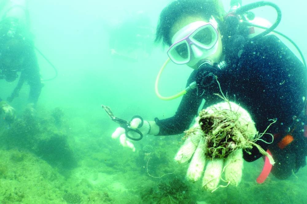 
A scuba diver shows to the camera abandoned fishing nets removed from a coral reef in Phuket, Thailand. 