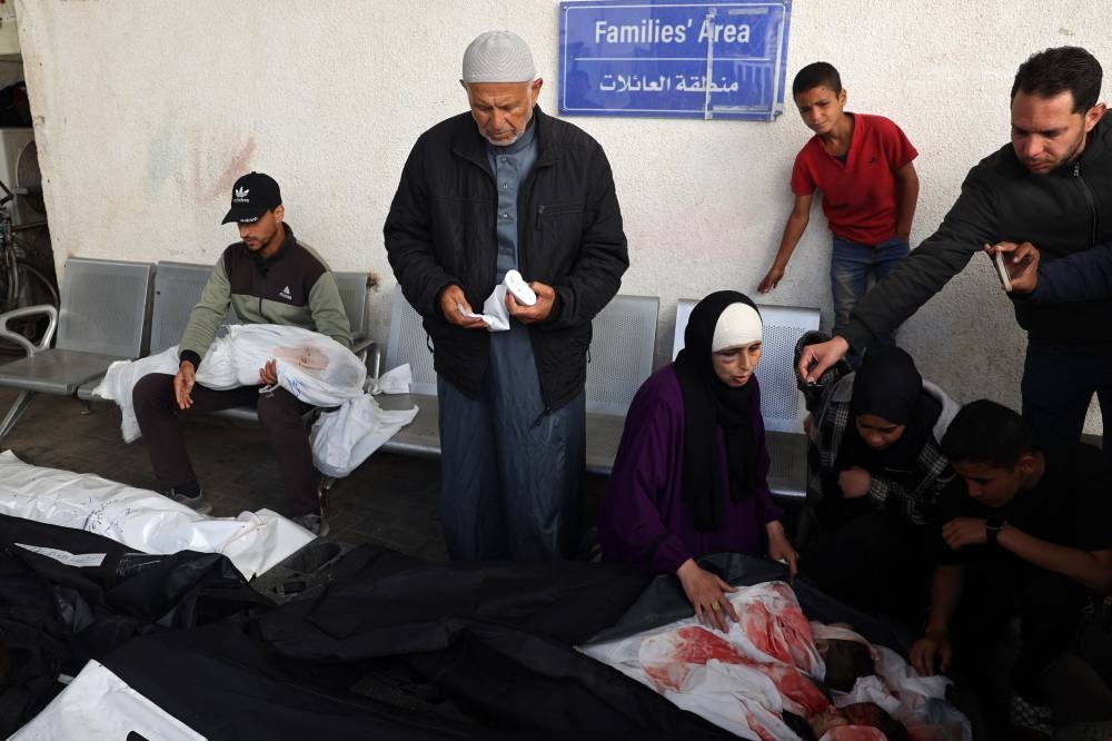 A Palestinian woman mourns over the bodies of children as a man holds the shrouded body of another, all killed in Israeli bombing in Rafah in the southern Gaza Strip on Saturday. AFP