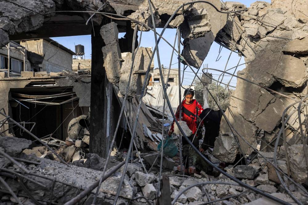 A woman and a girl search for items through the rubble of a collapsed building in Rafah in the southern Gaza Strip on Wednesday following reported Israeli air strikes overnight. AFP