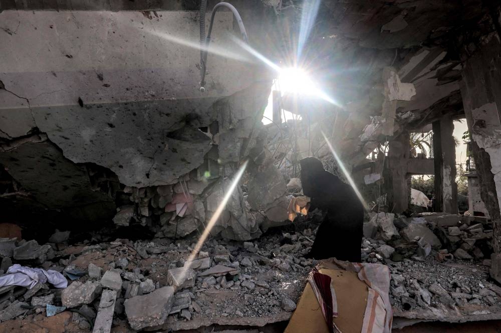 A woman searches through the rubble of a collapsed building in Rafah in the southern Gaza Strip on Wednesday following reported Israeli air strikes overnight. AFP