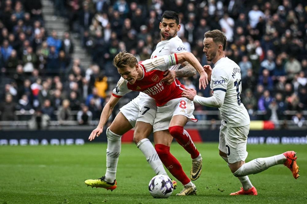 Tottenham Hotspur's defender Cristian Romero, James Maddison and Arsenal's midfielder Martin Odegaard vying for the ball during the Premier League match in London yesterday. (AFP) 