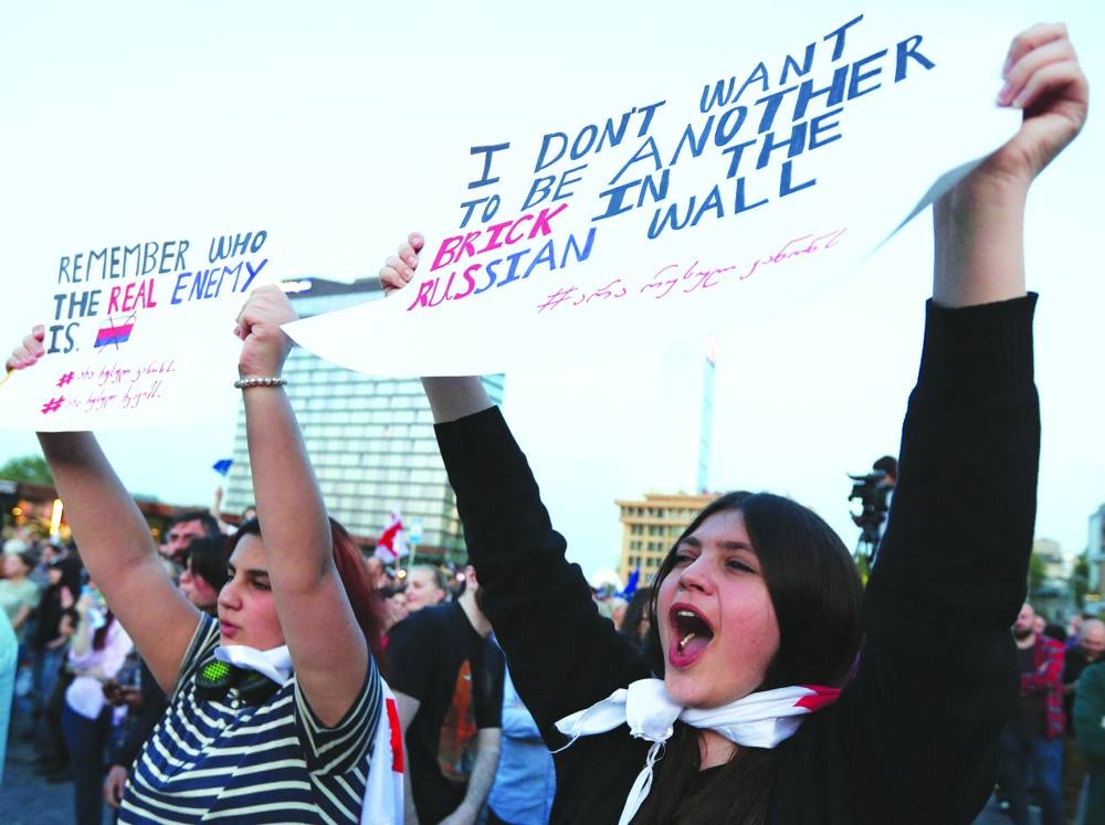 
Right: Demonstrators hold placards during a protest against a bill on ‘foreign agents’ in Tbilisi. 