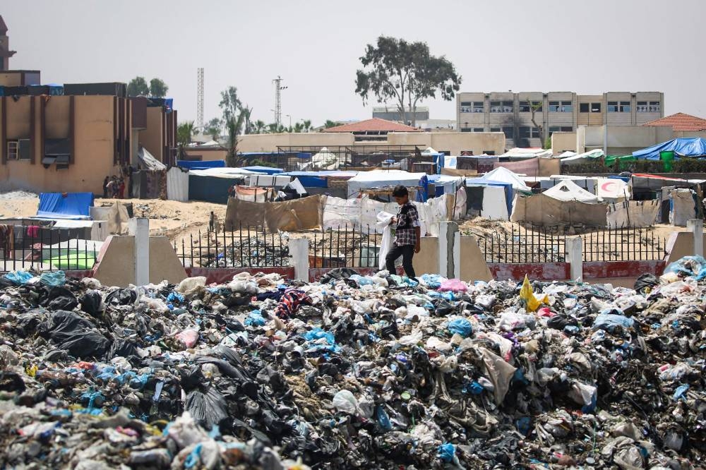 A child looks for objects in garbage piled up near tents set up by displaced Palestinians in Khan Yunis in the southern Gaza Strip, on Saturday. AFP