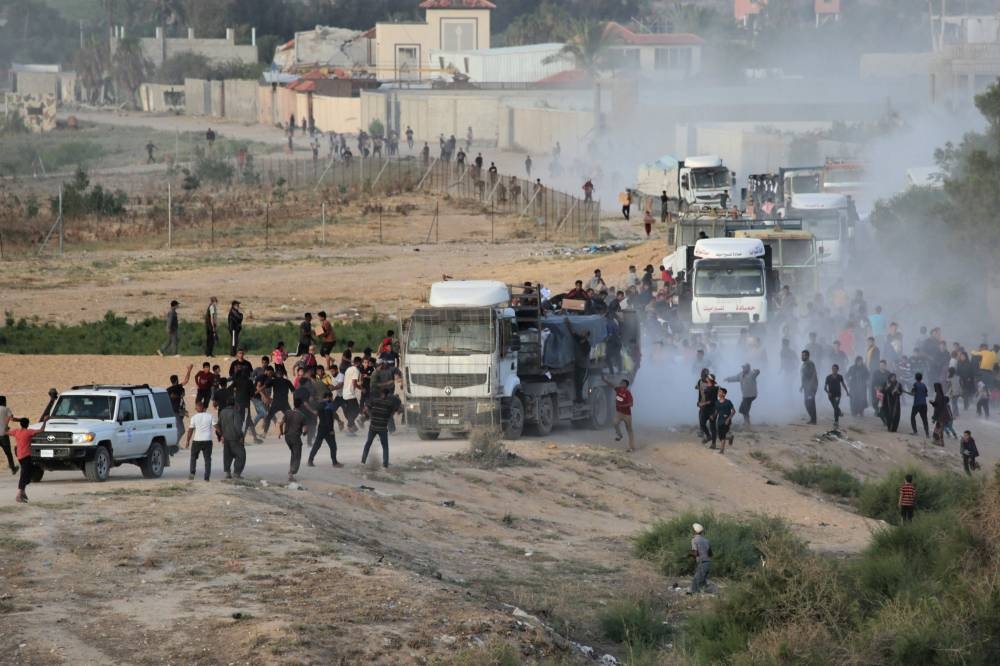Palestinians rush trucks as they transport international humanitarian aid from the US-built Trident Pier near Nuseirat in the central Gaza Strip on Saturday. AFP
