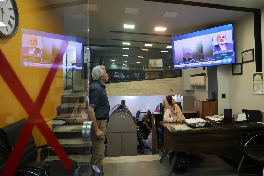 People follow the news of a crash of a helicopter carrying Iran's President Ebrahim Raisi, on a TV in a shop in Tehran, Iran. WANA via REUTERS.