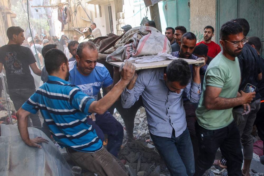 People carry the body of a Palestinian killed during Israeli bombardment at the Al-Daraj neighbourhood in Gaza City on Tuesday. AFP