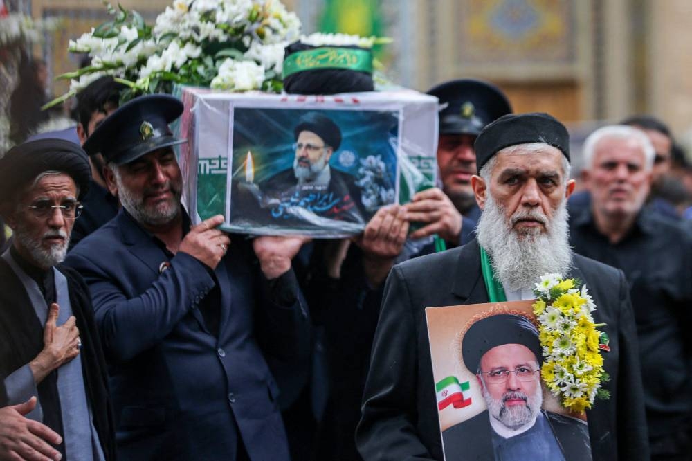 A member of a honour guards weeps while carrying the coffin of Iran's President Ebrahim Raisi during a funeral procession in Qom, on Tuesday. 
