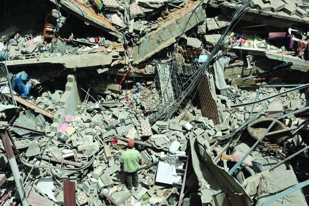 A Palestinian searches through debris at the site of an Israeli strike on the Al-Daraj neighbourhood in Gaza City yesterday