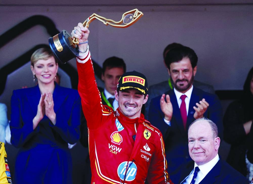 Ferrari’s Charles Leclerc celebrates on the podium with a trophy after winning the Monaco Grand Prix alongside Prince Albert II of Monaco at the Circuit de Monaco on Sunday. (Reuters)