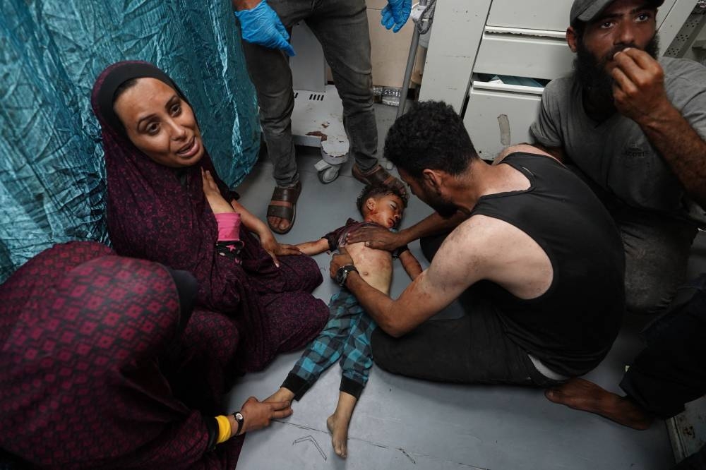 The mother (L) of Palestinian toddler Khaled Abu Samaha weeps as attempts to save his life continue upon his arrival at the Al-Aqsa Martyrs Hospital in the central Gaza Strip after he was badly injured in Israeli bombardment on a house in Nuseirat city on Monday. AFP